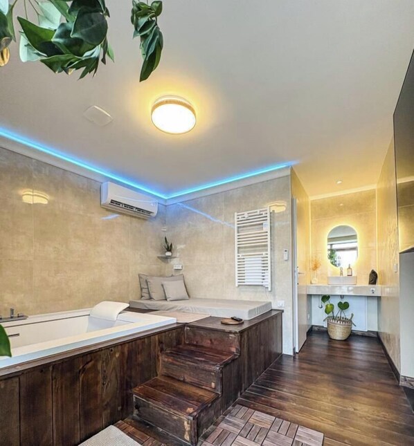 Une salle de bain moderne avec une grande baignoire, des marches en bois et un luminaire au plafond.