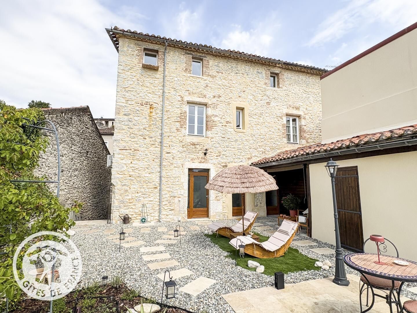 A stone building with a patio area featuring lounge chairs and a small table.