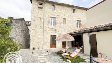 A stone building with a patio area featuring lounge chairs and a small table.