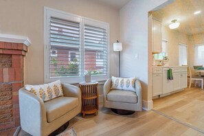 A living room with two sofas, a small round table, and a lamp. There is a kitchen area with cabinets and a countertop visible. - Peaceful UNR Retreat 2 Bed 2 Bath (Reno)