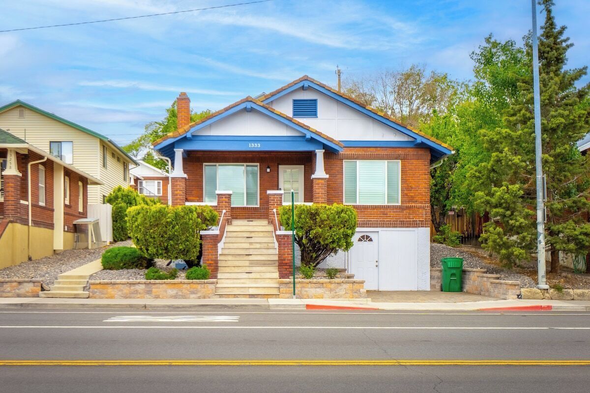 Ein zweistöckiges Haus mit Veranda, Garage und kleinem Vorgarten mit Sträuchern.