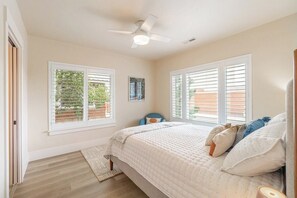 A bedroom with a bed, two windows with blinds, a ceiling fan, and a rug. - Peaceful UNR Retreat 2 Bed 2 Bath (Reno)