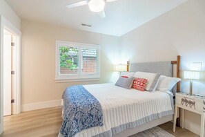 A bedroom with a bed, bedside tables, a ceiling fan, and a window with blinds. - Peaceful UNR Retreat 2 Bed 2 Bath (Reno)