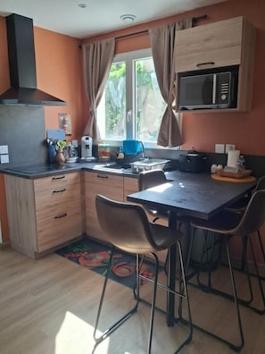 A compact kitchen with a microwave, a coffee machine, and a small dining table with chairs. - Gîtes de France® - French Overseas Departments and Territories (SAINT SOZY)