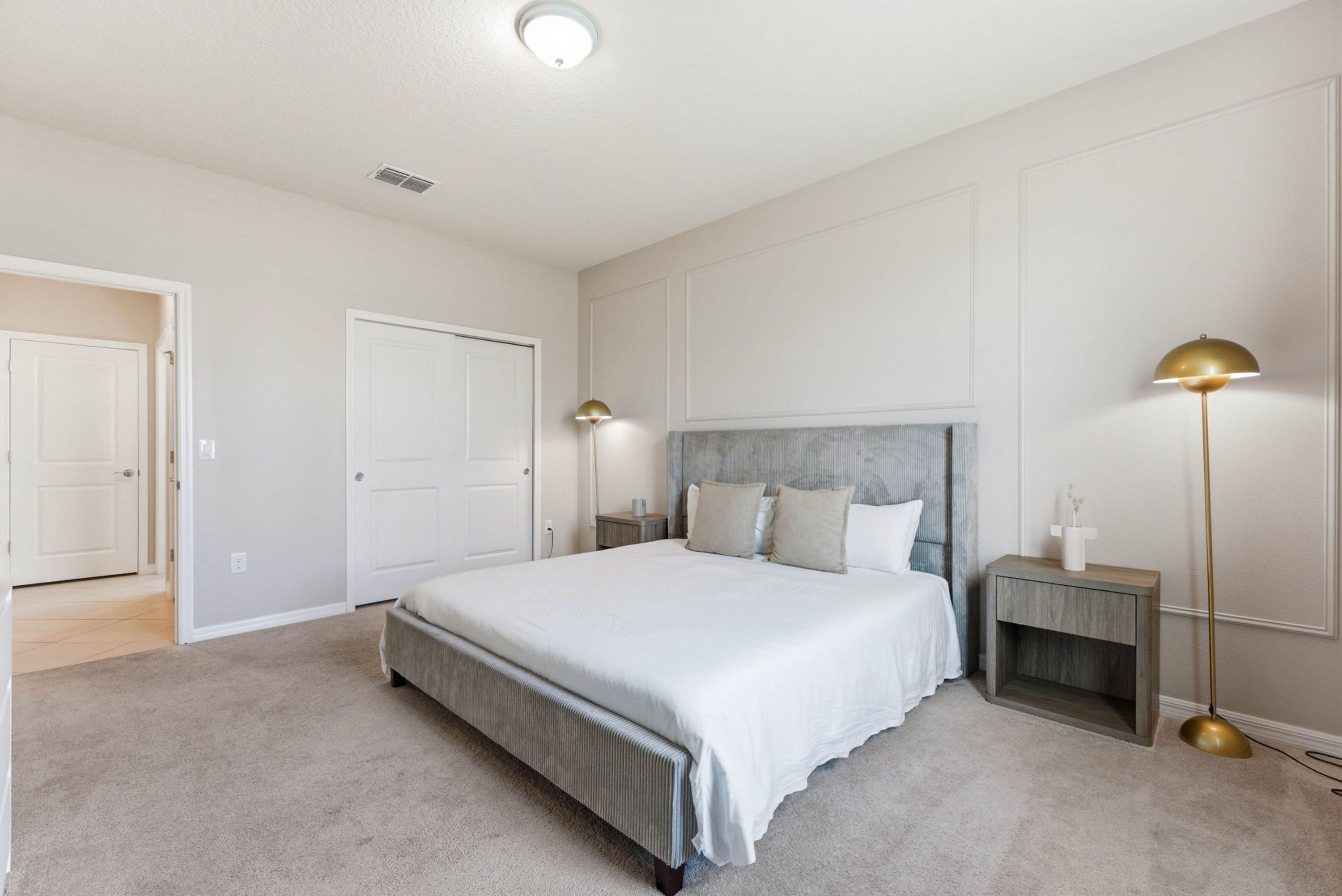 A bedroom with a large bed, bedside tables, a nightstand, and a floor lamp.