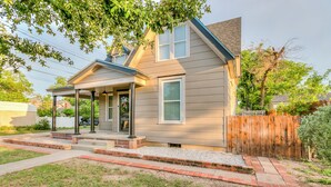 A single-story house with a covered porch, a front door, and a small front yard with a wooden fence. - Spacious 4 BR/2 BA + Grill/Firepit (San Angelo)