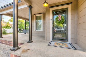 A building entrance with a glass door, a welcome mat, and a bench outside. - Spacious 4 BR/2 BA + Grill/Firepit (San Angelo)