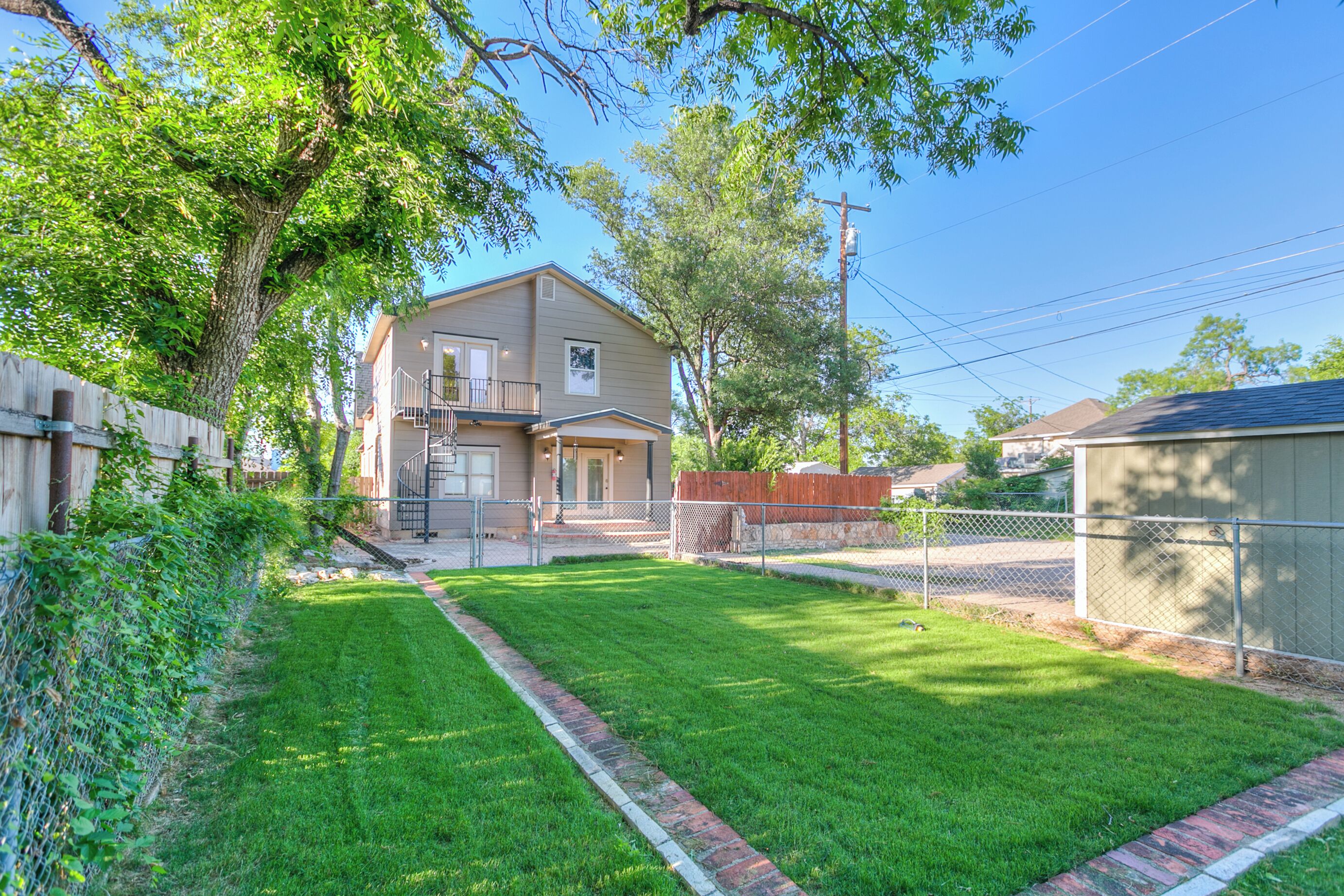 A residential property with a well-maintained lawn, a wooden fence, and a two-story house with a garage.
