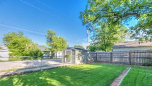 A residential backyard with a well-maintained lawn, a small shed, and a wooden fence. - Spacious 4 BR/2 BA + Grill/Firepit (San Angelo)