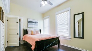 A bedroom with a bed, a ceiling fan, a window with blinds, and a door. - Spacious 4 BR/2 BA + Grill/Firepit (San Angelo)