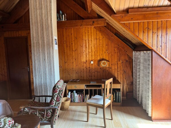 Une pièce mansardée chaleureuse avec des murs en bois, un bureau, une chaise et une bibliothèque.