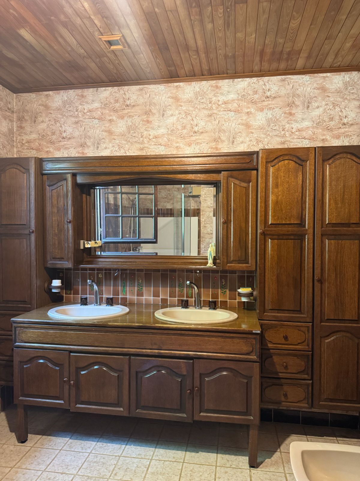 A bathroom with wooden cabinetry, a double sink vanity, and a large mirror.