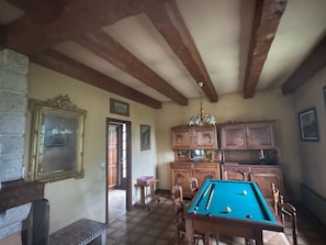 A room with a pool table, wooden cabinets, and a stone fireplace.