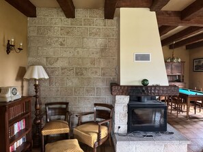 Une pièce chaleureuse avec un mur en pierre, une cheminée, des meubles en bois et une table de billard.