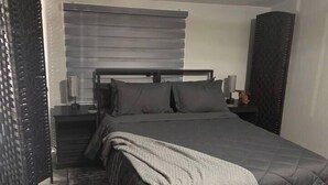 Een slaapkamer met een bed, nachtkastjes en een nachtkastje.