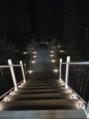 A wooden staircase with white railings and lights along the steps, leading upwards. - John Boxtel Retreat – A One-of-a-Kind (Greater Napanee)