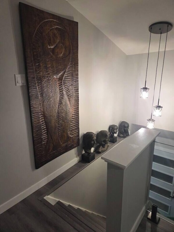 A modern interior with a large abstract artwork, a minimalist reception desk, and a staircase. - John Boxtel Retreat – A One-of-a-Kind (Greater Napanee)