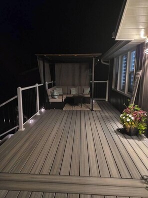 A wooden deck with a covered seating area and a potted plant. - John Boxtel Retreat – A One-of-a-Kind (Greater Napanee)