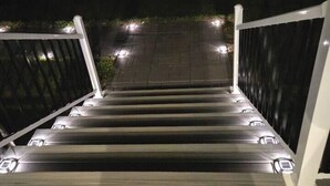 Een trap met leuningen en verlichting, die leidt naar een donkerder gebied.