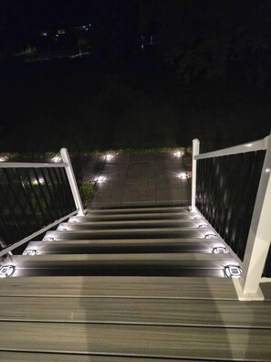 Eine Treppe mit Geländern und Beleuchtung, die in einen dunklen Bereich führt.