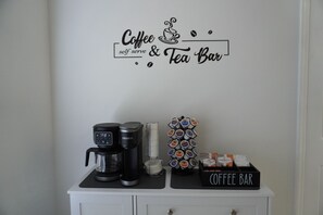 A coffee and tea bar setup with a coffee maker, a tea dispenser, and a coffee bar sign. - Pool home near Disney with Game Room + EV Charger (Davenport)