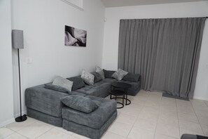 A modern living room with a sectional sofa, a small table, and a floor lamp. - Pool home near Disney with Game Room + EV Charger (Davenport)