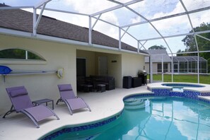 A covered outdoor area with a swimming pool, lounge chairs, and a patio with outdoor furniture. - Pool home near Disney with Game Room + EV Charger (Davenport)