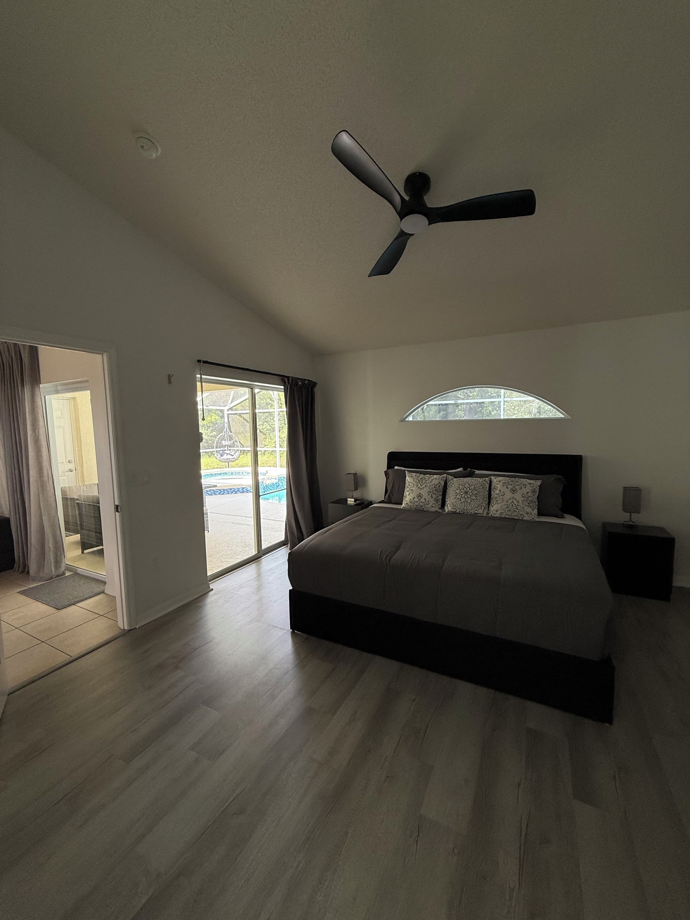 Ein Schlafzimmer mit einem großen Bett, einem Deckenventilator, einem Fenster und Blick ins Freie.