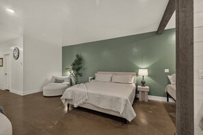 Ein Schlafzimmer mit Bett, Nachttischen, einer Lampe, einer Uhr und einer Pflanze.