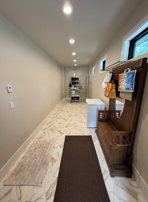 A narrow hallway with a marble floor, a wooden bench, a white refrigerator, and a metal rack with bags. - New build cabin with AC on 20+ acres outside Custer (Custer)