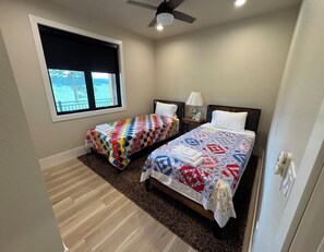A bedroom with two beds, a window with a view, a ceiling fan, and a nightstand with a lamp. - New build cabin with AC on 20+ acres outside Custer (Custer)