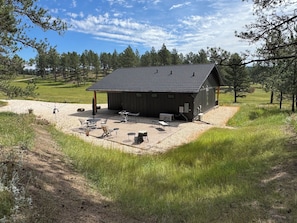 A rustic cabin with a gravel patio, outdoor seating, and a view of a forested area. - New build cabin with AC on 20+ acres outside Custer (Custer)
