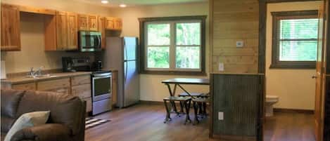 A compact kitchen with wooden cabinets, a microwave, and a refrigerator.
