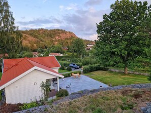 A residential area with houses, a paved driveway, and a hillside.