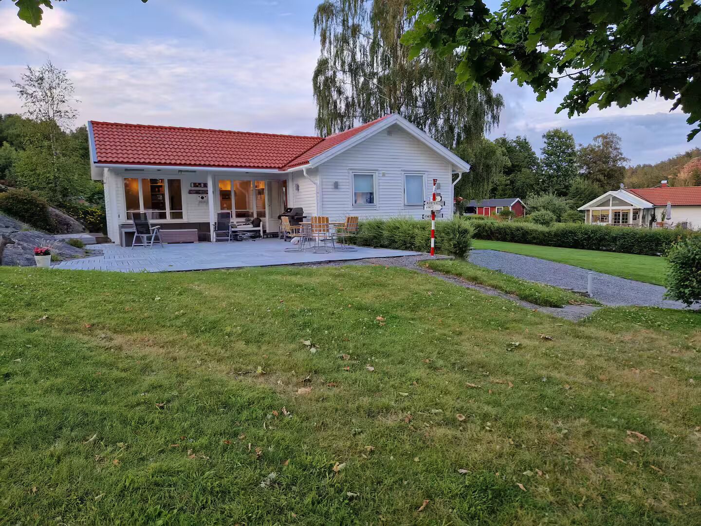 Une maison d’habitation avec un toit recouvert de tuiles rouges, un patio abrité et une pelouse bien entretenue.
