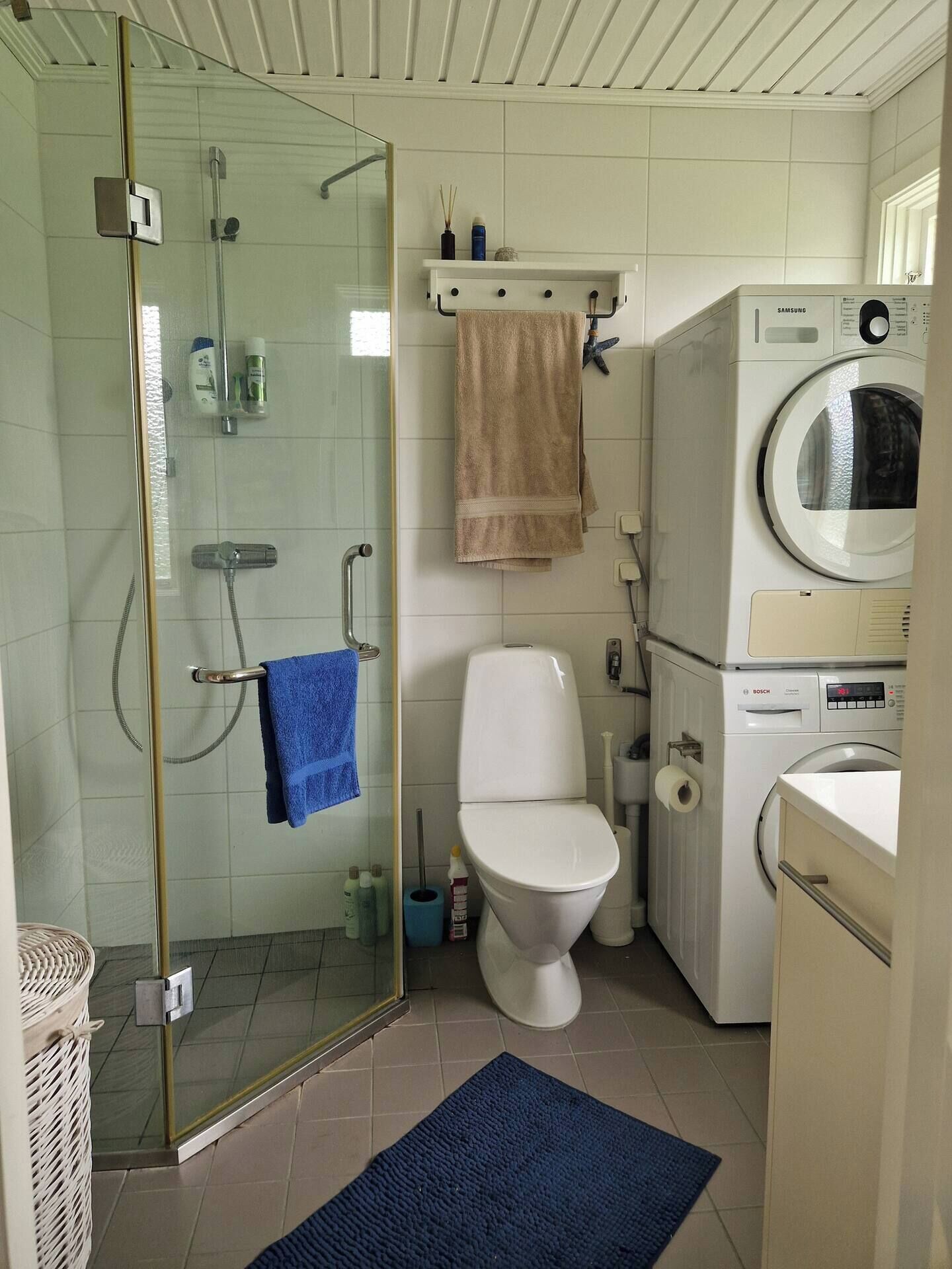 Une salle de bain avec une douche à parois de verre, des toilettes, un lave-linge et un lavabo.