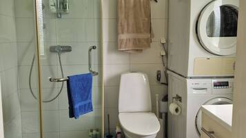 Une salle de bain avec une douche à parois de verre, des toilettes, un lave-linge et un lavabo.