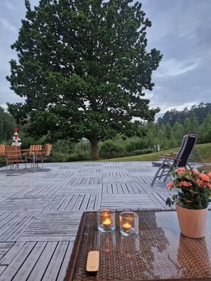 An outdoor seating area with wooden furniture and a large tree in the background.