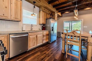 Eine moderne Küche mit Holzschränken, einem Edelstahlkühlschrank und einer Bar mit Holzstühlen.