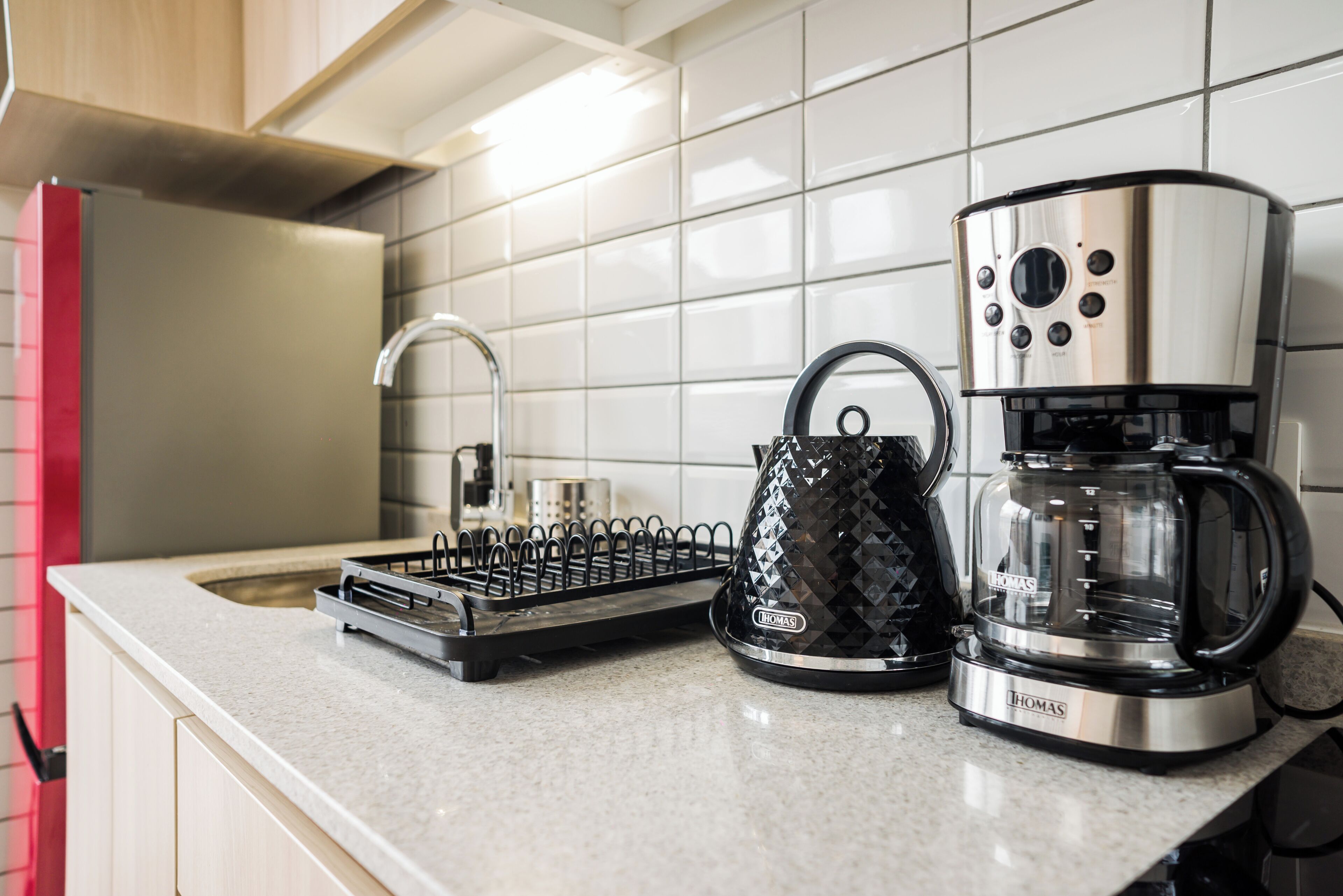 Una encimera de cocina con cafetera, hervidor y tostadora.