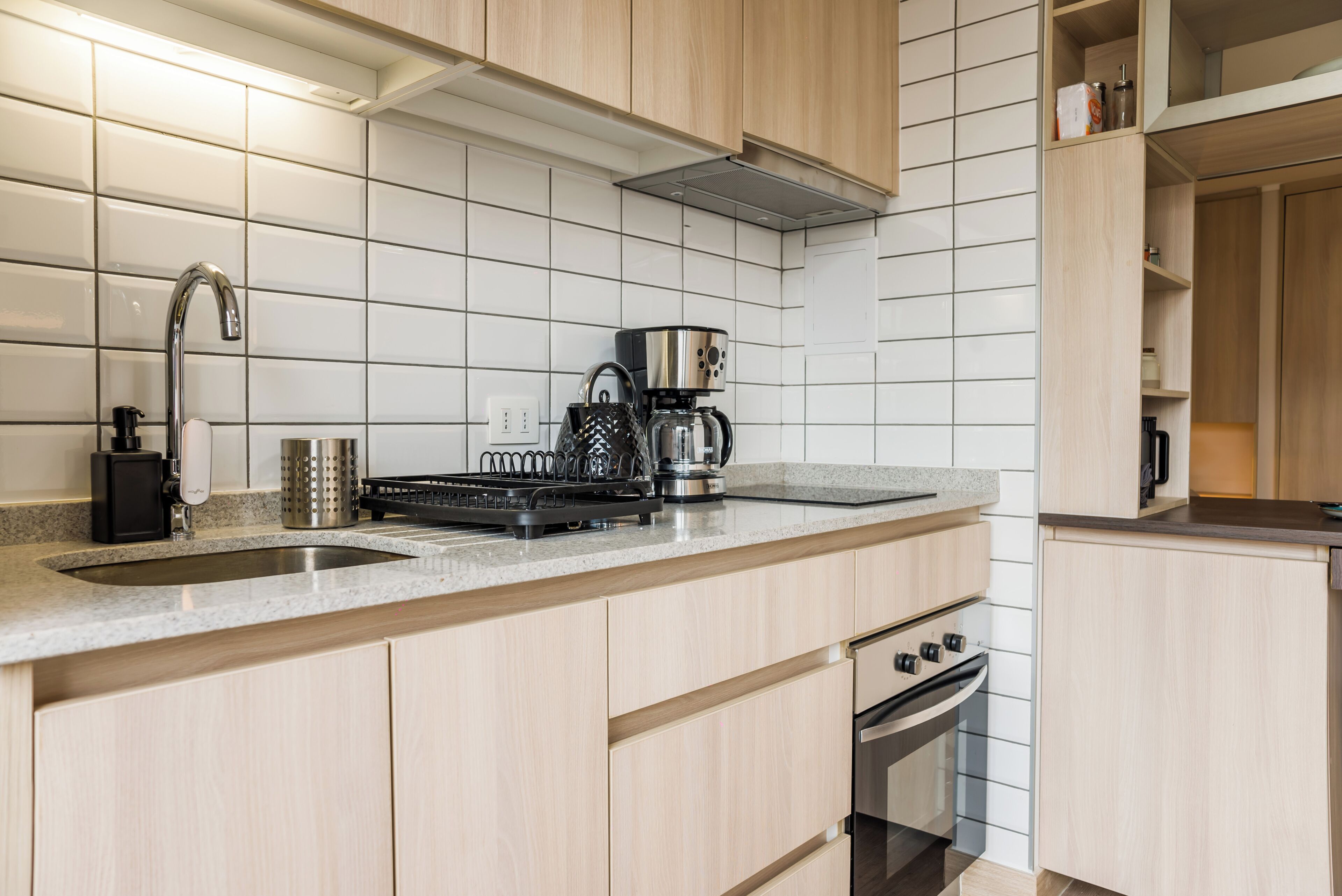 Una cocina moderna con campana de acero inoxidable, cafetera y horno empotrado.
