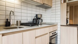 Eine moderne Küche mit Dunstabzugshaube aus Edelstahl, einer Kaffeemaschine und einem eingebauten Backofen.