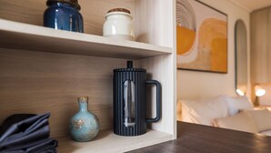 Ein Regal mit einer schwarzen Tasse, einer blauen Vase und einem weißen Behälter.