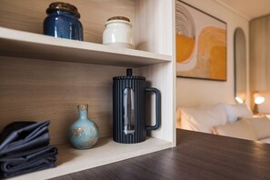 Ein Regal mit einer schwarzen Tasse, einer blauen Vase und einem weißen Behälter.