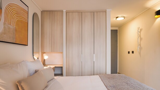 Ein Schlafzimmer mit Bett, Nachttischen, einem Kleiderschrank und einer Wandleuchte.