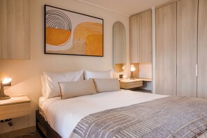 A neatly arranged bedroom with a bed, bedside lamps, a nightstand, a wall-mounted artwork, and a wardrobe. - Cozy Nunoa Apt for 2 with Balcony Views (Ñuñoa)