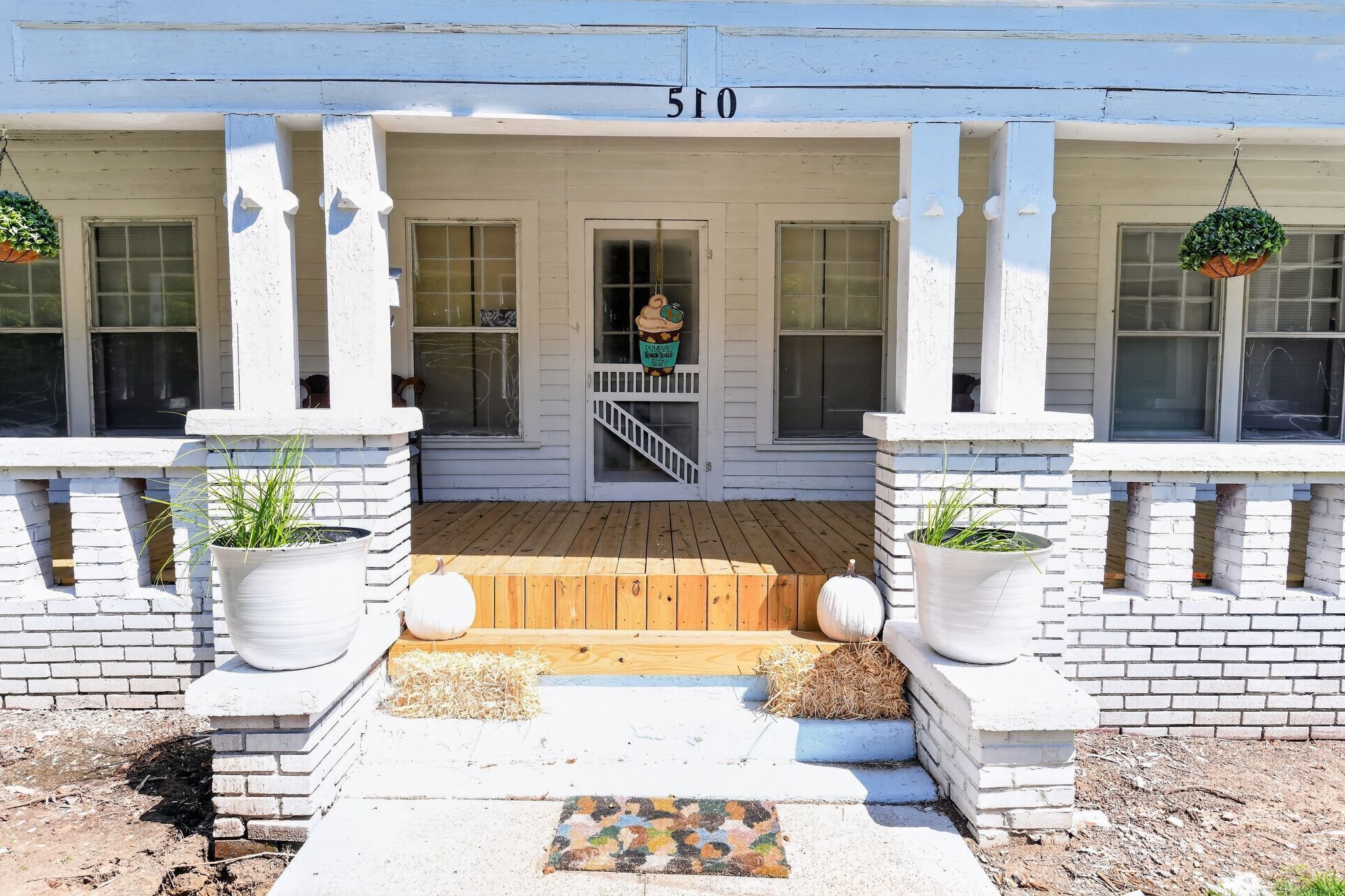 A building with a porch, a number '510' above the entrance, and potted plants on either side.