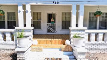 A building with a porch, a number '510' above the entrance, and potted plants on either side.