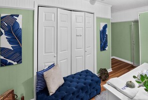 Una habitación con un sofá azul con capitoné, una puerta blanca con la leyenda 'Despensa de los Propietarios' y obras de arte en las paredes.