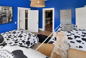 A room with two beds, a hanging light fixture, a wardrobe, and a door leading to another room. - Cozy Aberdeen MS Retreat Near Lake & MSU (Aberdeen)